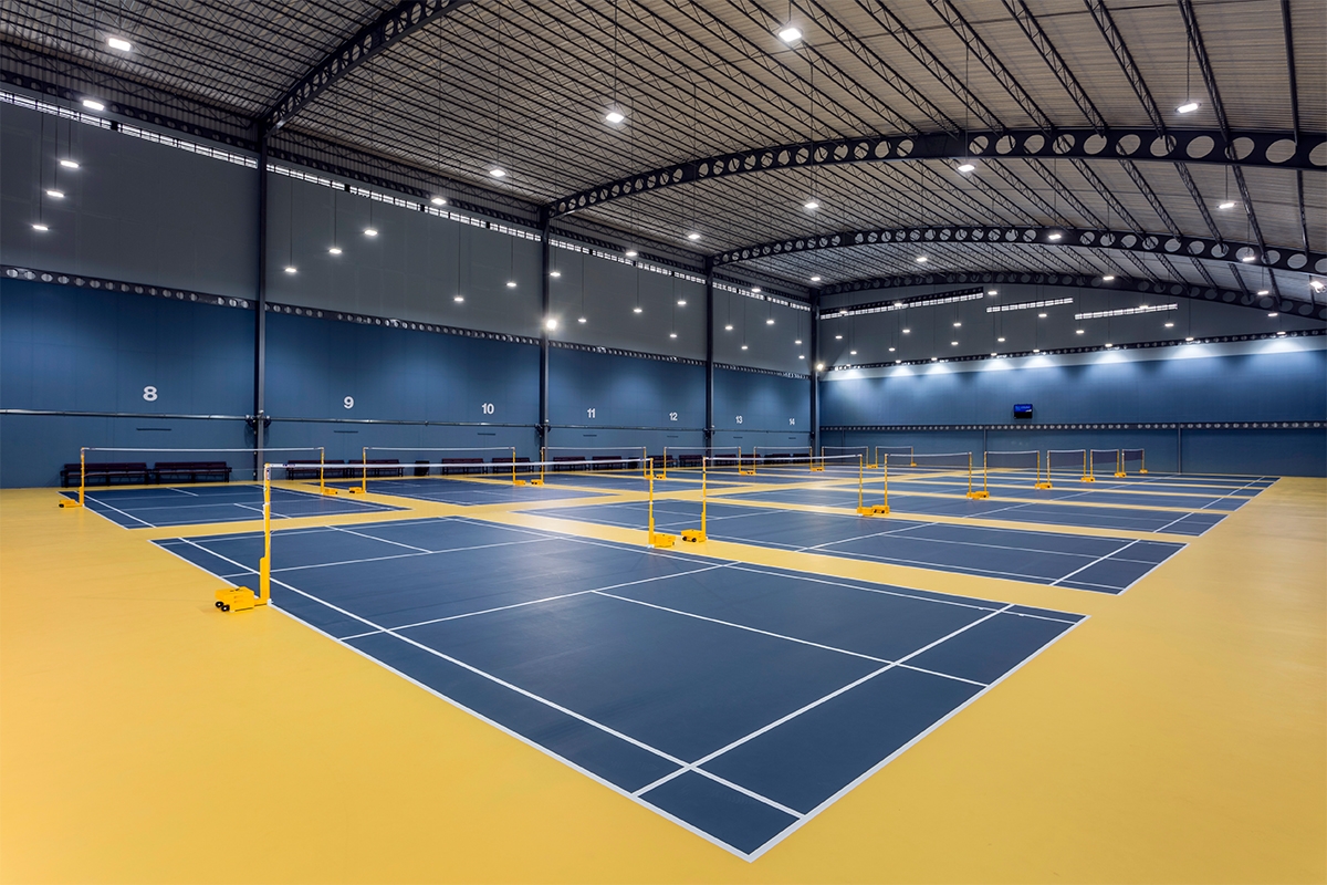 Bright real indoor badminton venue with multiple standard courts and centered nets